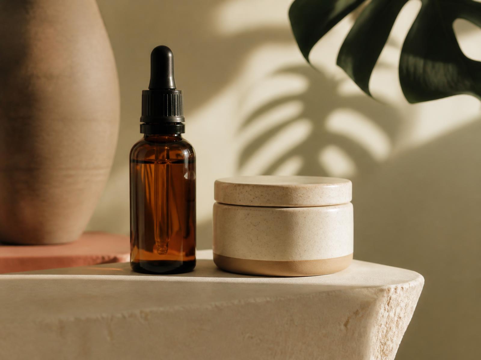Amber serum bottle and ceramic cream jar in warm morning light